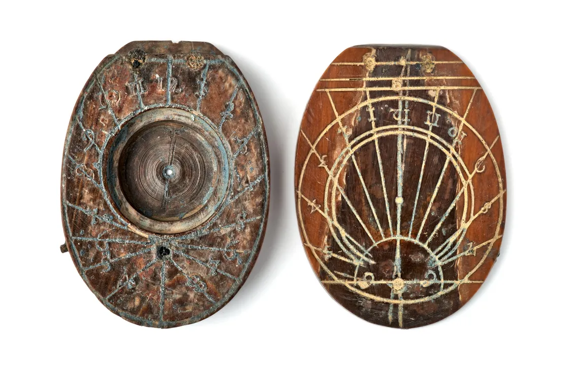 Two vintage wooden sundials with engraved lines and numbers, one open showing its dial and gnomon, the other closed displaying its ornate cover design.