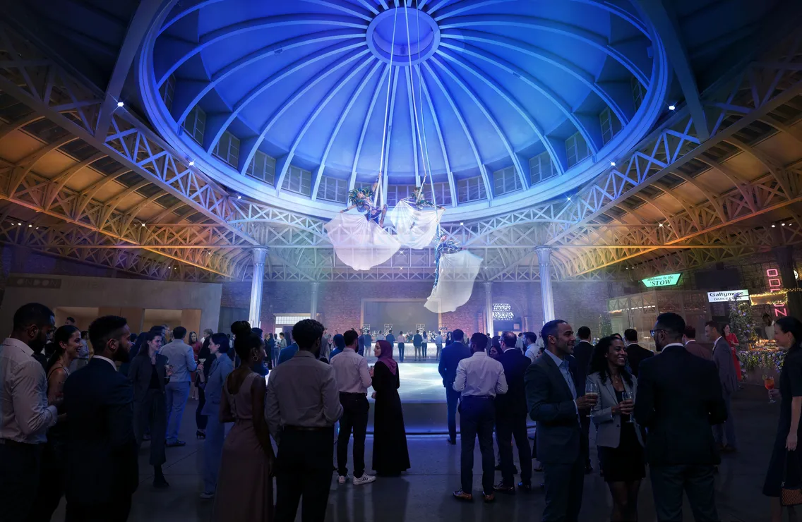 The interior of a dome-like building with two trapeze artists hanging above mingling guests