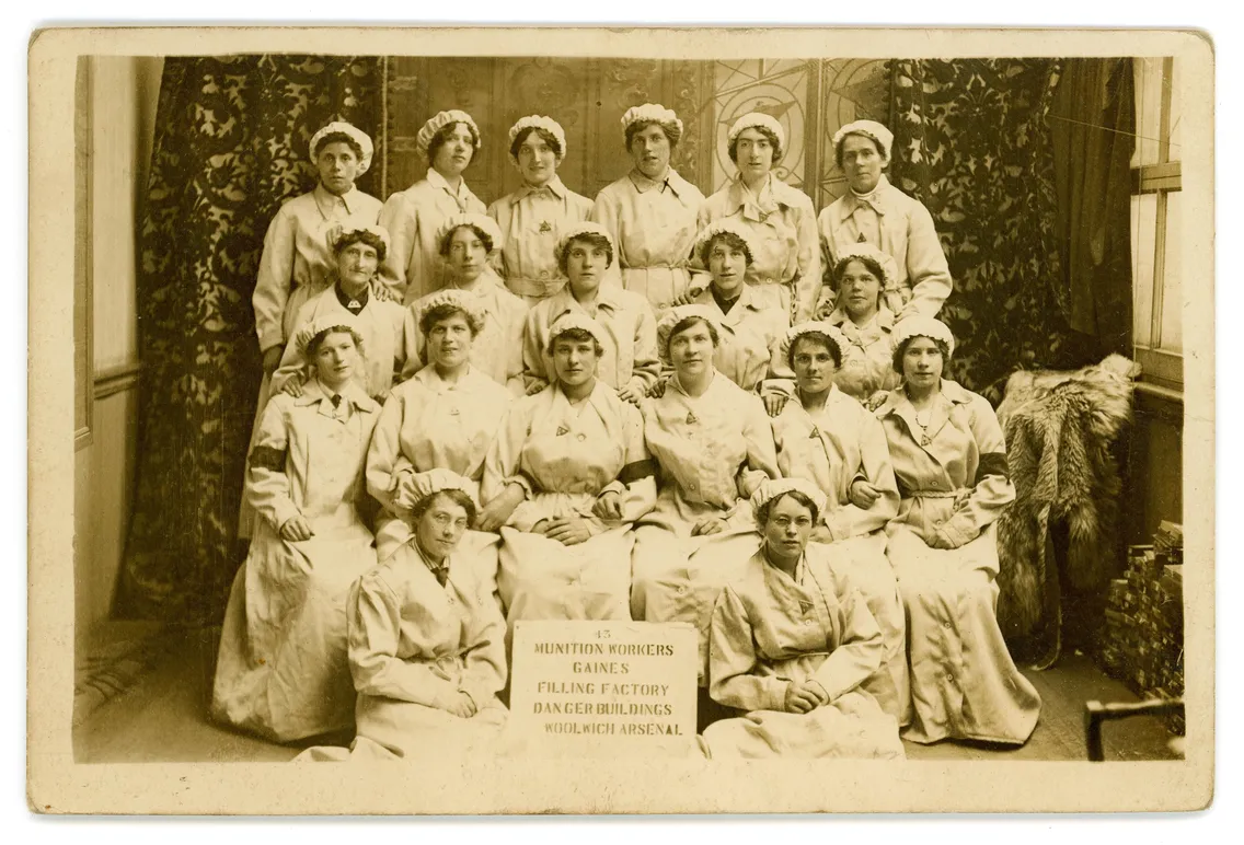 A group of women munitions workers in uniform pose for a formal photo at the Filling Factory Danger Buildings, Woolwich Arsenal, early 20th century.