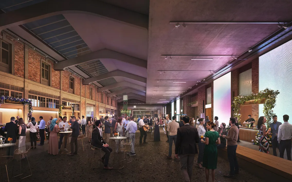Large open space with guests stood mingling, entertainers playing guitar and a bar to the right