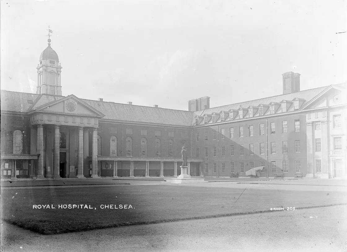 Historical photo of the royal hospital chelsea featuring its classic architecture and a statue in the courtyard, clear sky in the background.