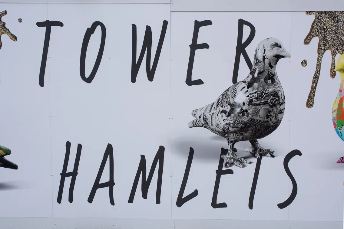 A wall mural with the words "TOWER HAMLETS" and an illustrated pigeon covered in black and white patterns.