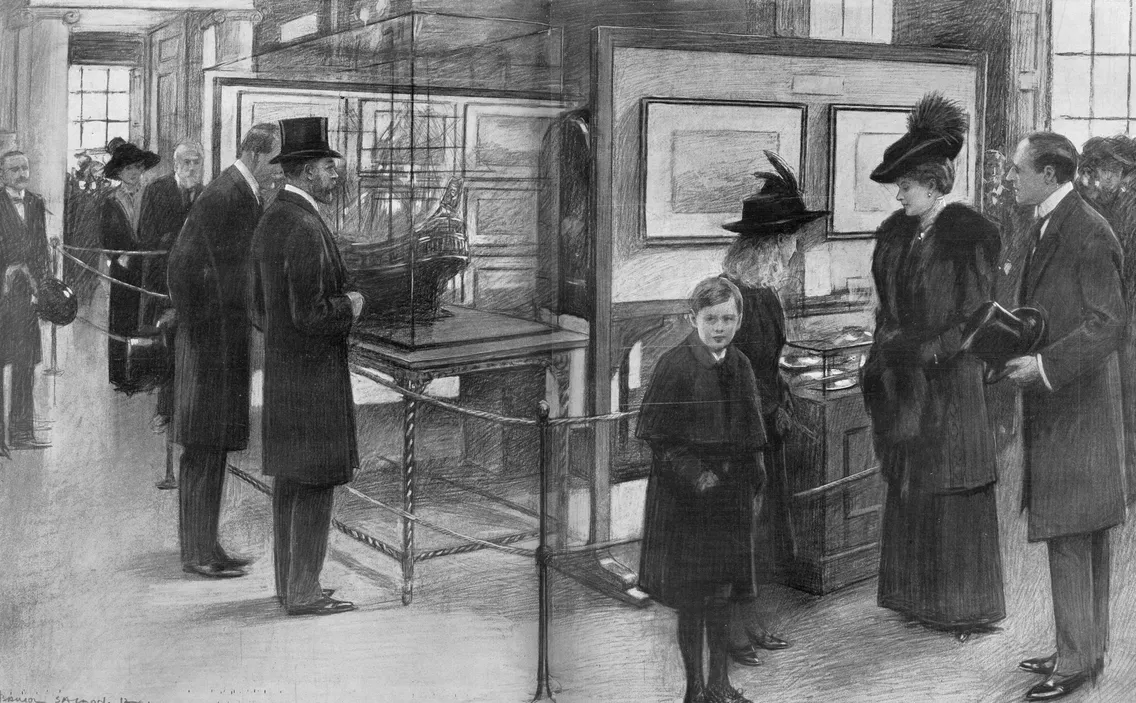 A group of people, dressed in early 20th-century clothing, are viewing an exhibition in a gallery. A child stands in the foreground while adults examine sculptures and framed artworks behind a rope barrier.