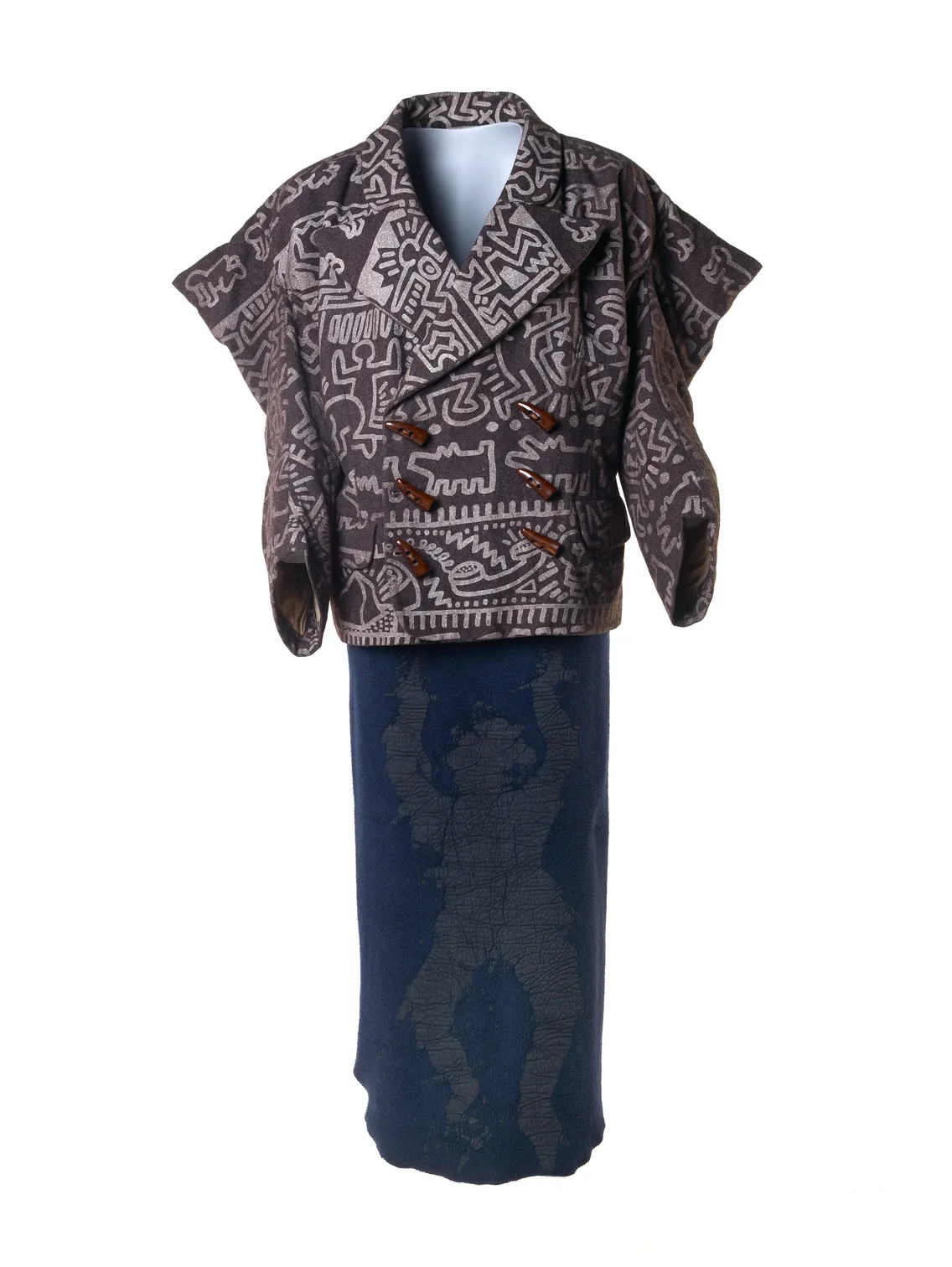 A traditional african robe with detailed geometric patterns on the top and a dark blue skirt with subtle designs, displayed on a mannequin against a white background.