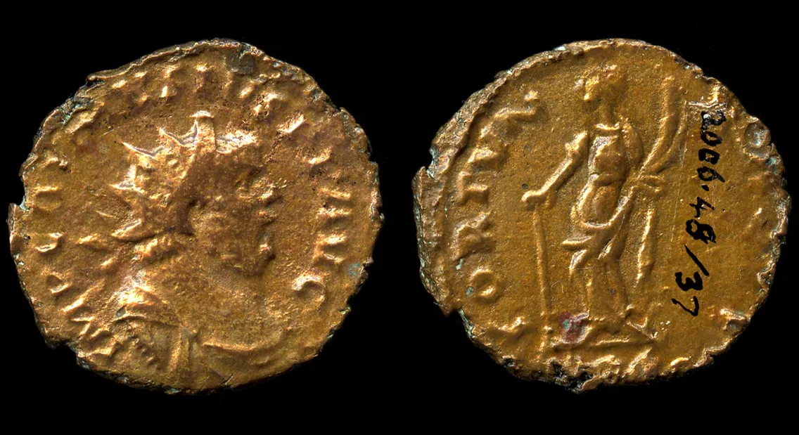 Ancient coin with inscriptions, featuring a head on the obverse and a standing figure on the reverse, set against a black background.