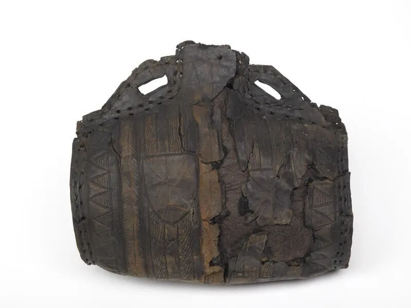 A weathered leather bag with intricate embossed patterns and worn, curved handles on a plain background.
