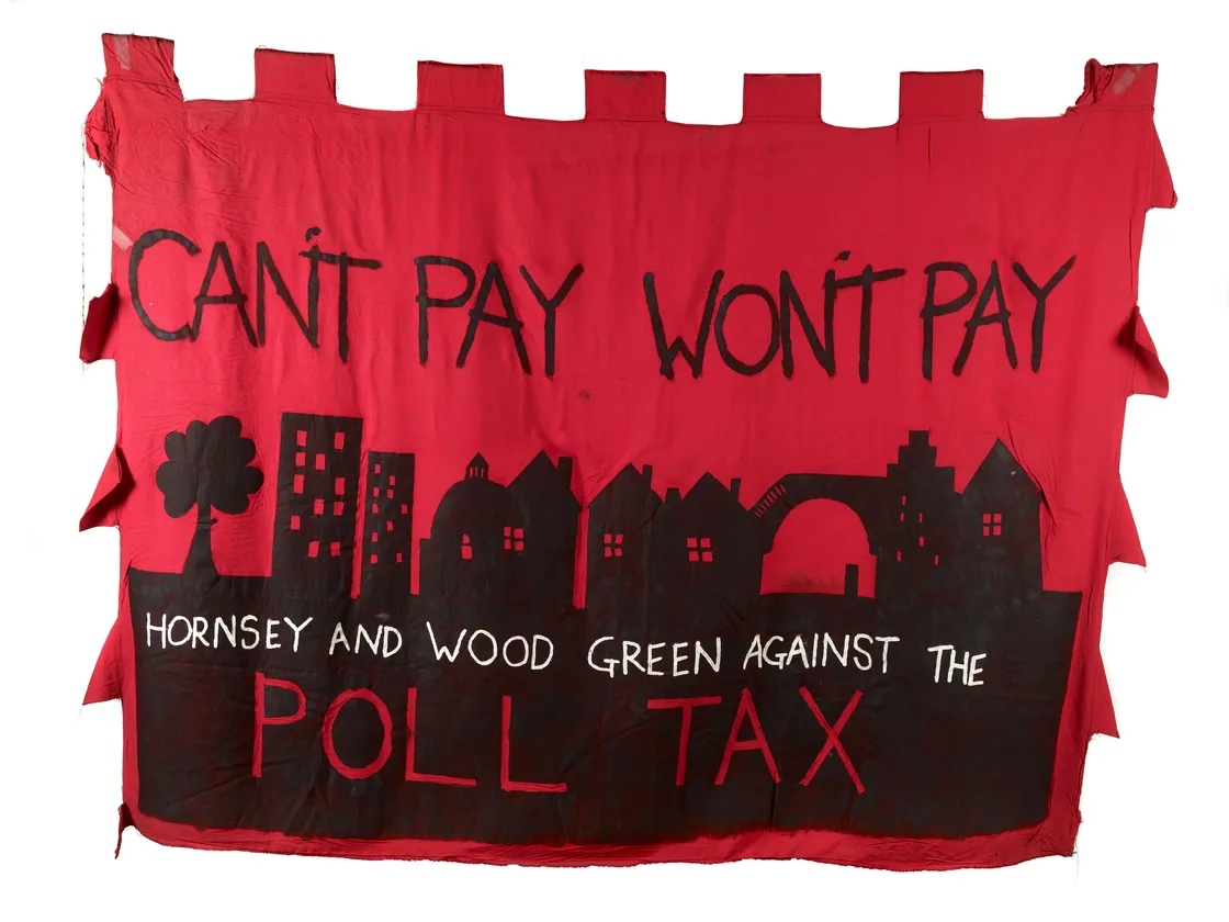 A red protest banner with the slogan "can't pay won't pay" and "hornsey and wood green against the poll tax," featuring symbols like a tree, buildings, and an arch.