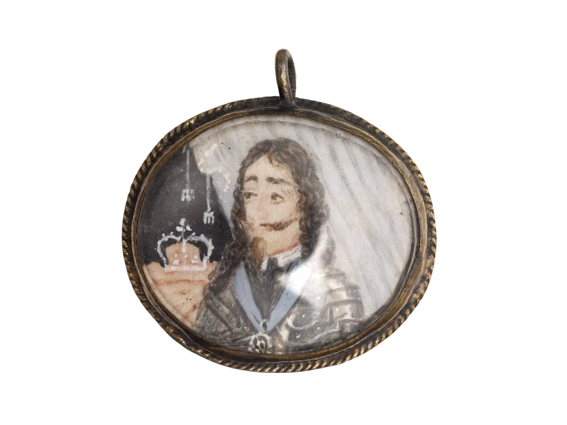 Antique oval portrait locket depicting a man in historical military attire, isolated on a white background.