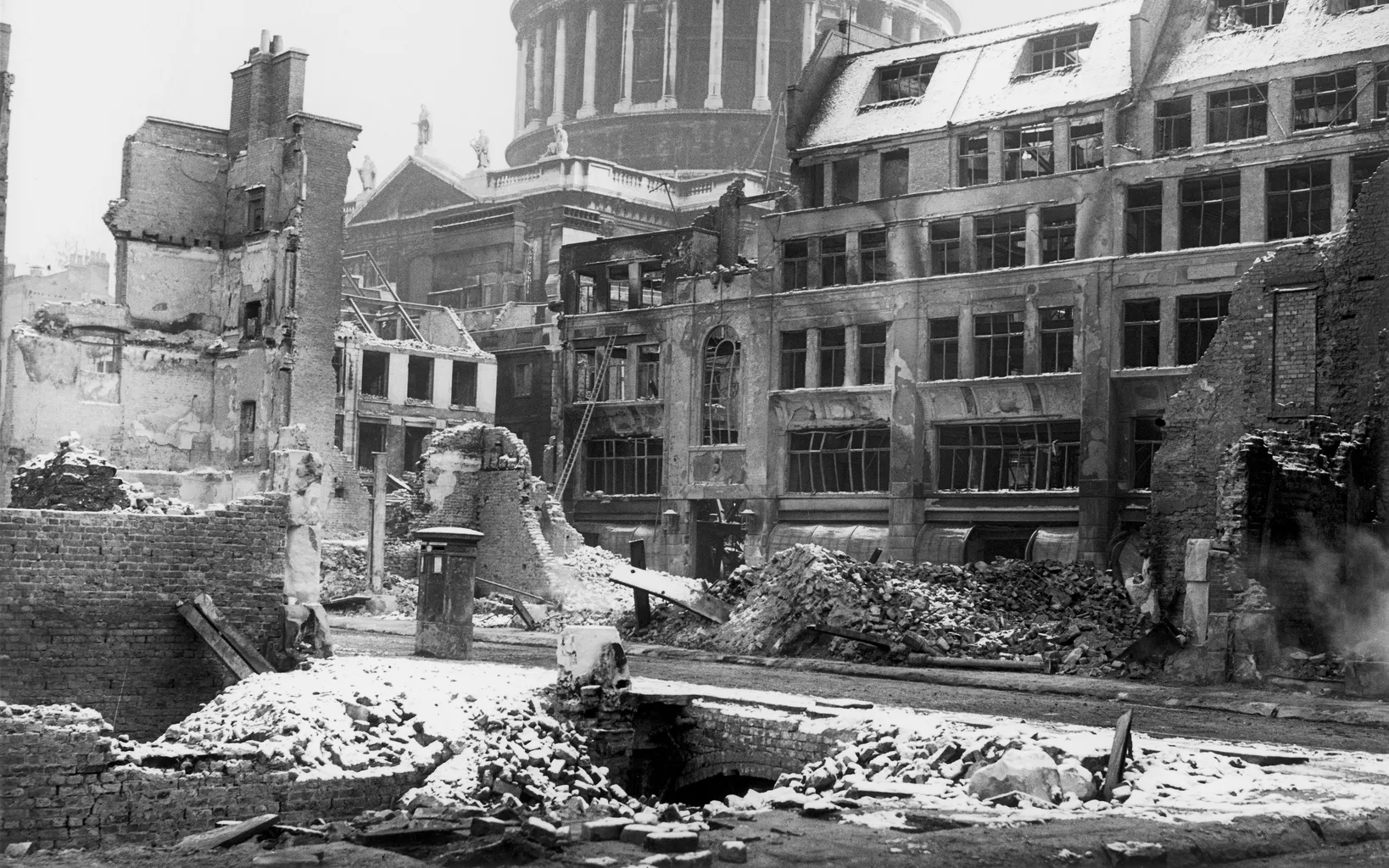 Black and white photo of bomb-damaged buildings near st. paul’s cathedral in london during world war ii.