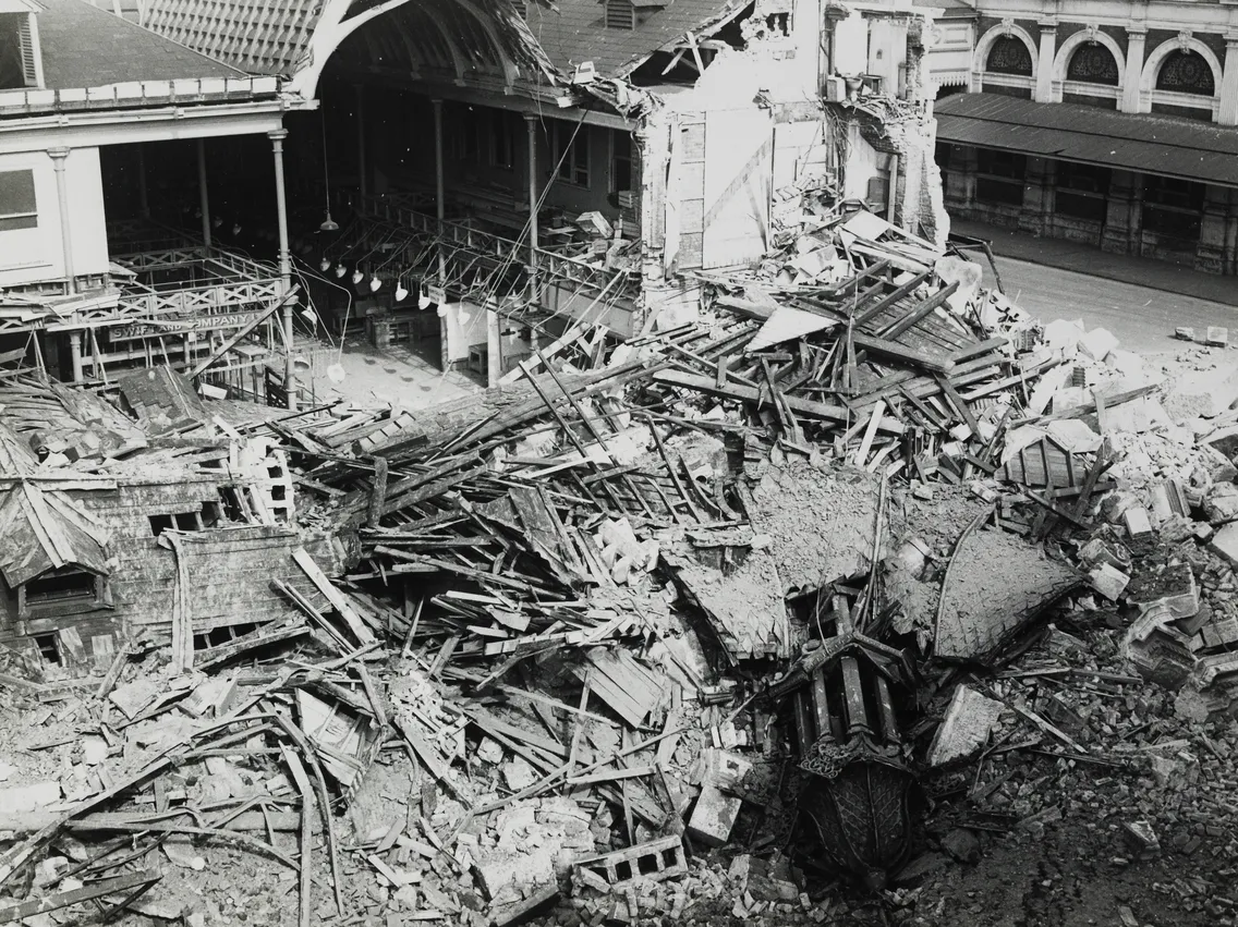 Black and white image of a demolished building with scattered debris and structural remnants.