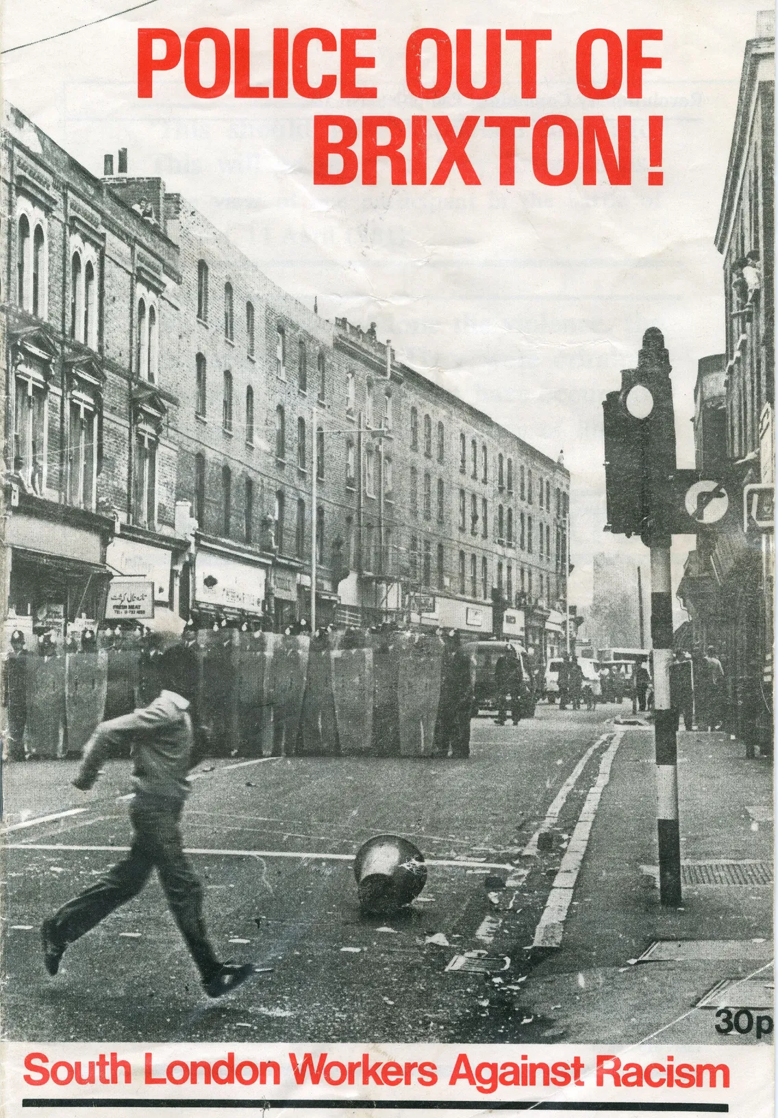 A black and white photo of a street protest with the caption "police out of brixton!" showing a person running and scattered debris.