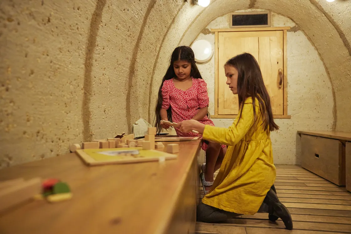Two young girls crouched in a recreation of a bunker