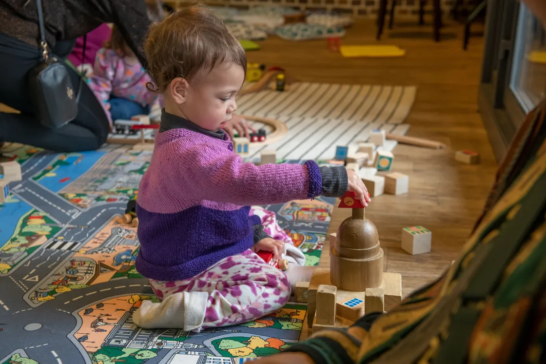 A baby wearing pink playing with a toy version of St Paul's Cathedral