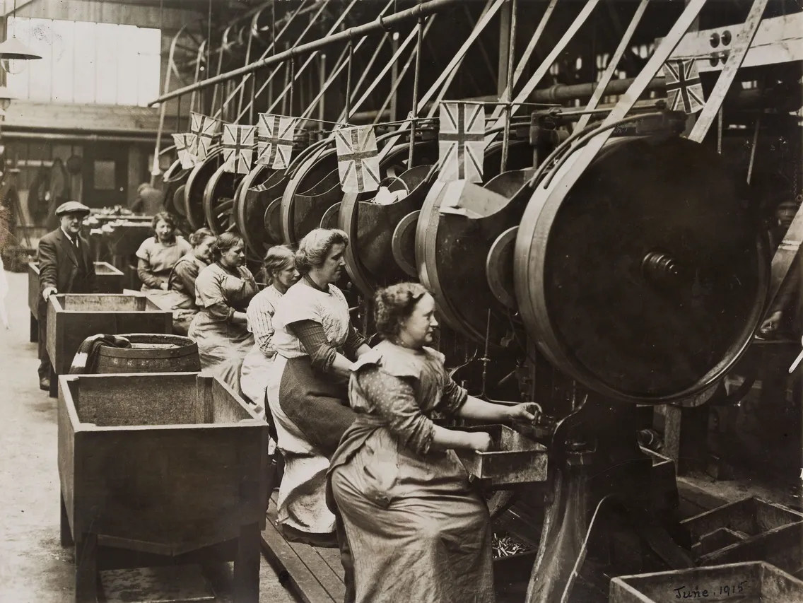 Women working on large machines in a factory, dated june 1918, surrounded by uk flags.