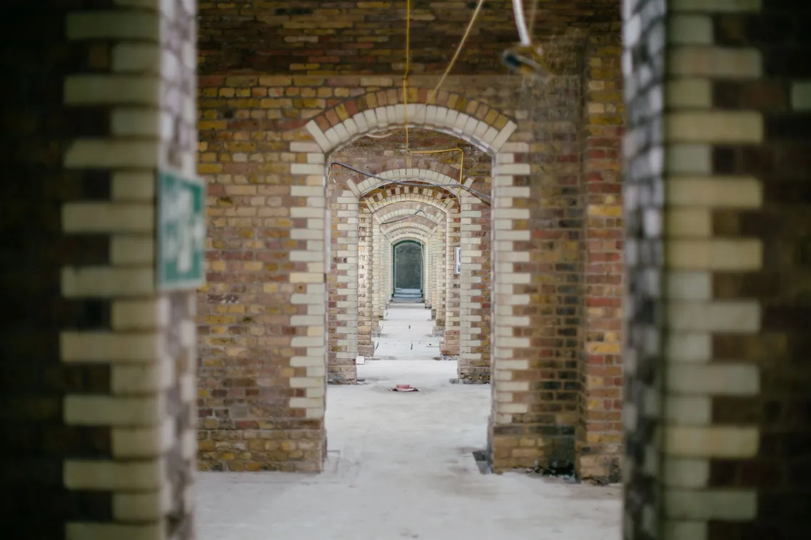 Long hallway with multiple brick archways and a partially finished floor.