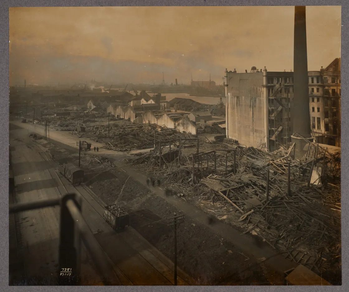 Historical photograph showing expansive industrial wreckage, with damaged buildings and scattered debris, viewed from an elevated perspective.