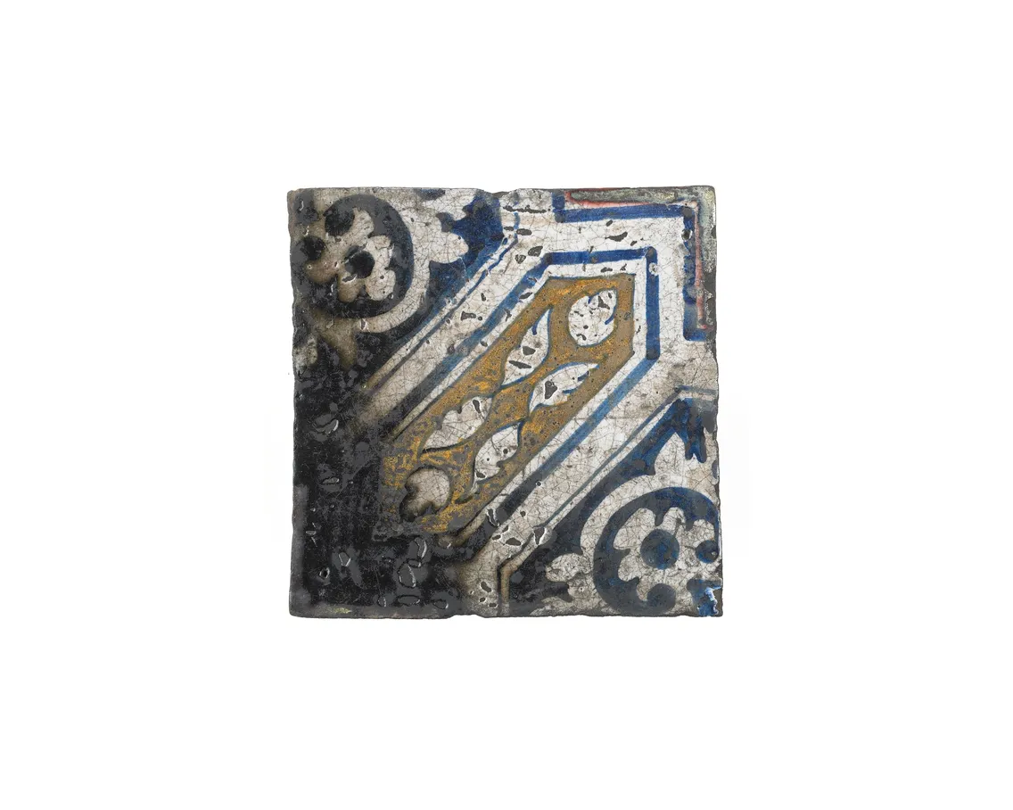 An ancient ceramic tile with intricate blue, white, and gold geometric patterns, showing signs of age and wear.