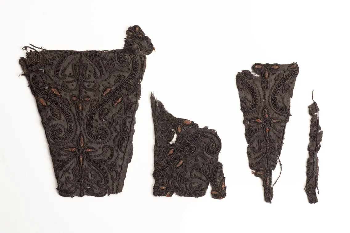 Four pieces of antique, intricately patterned black lace fabric against a white background.