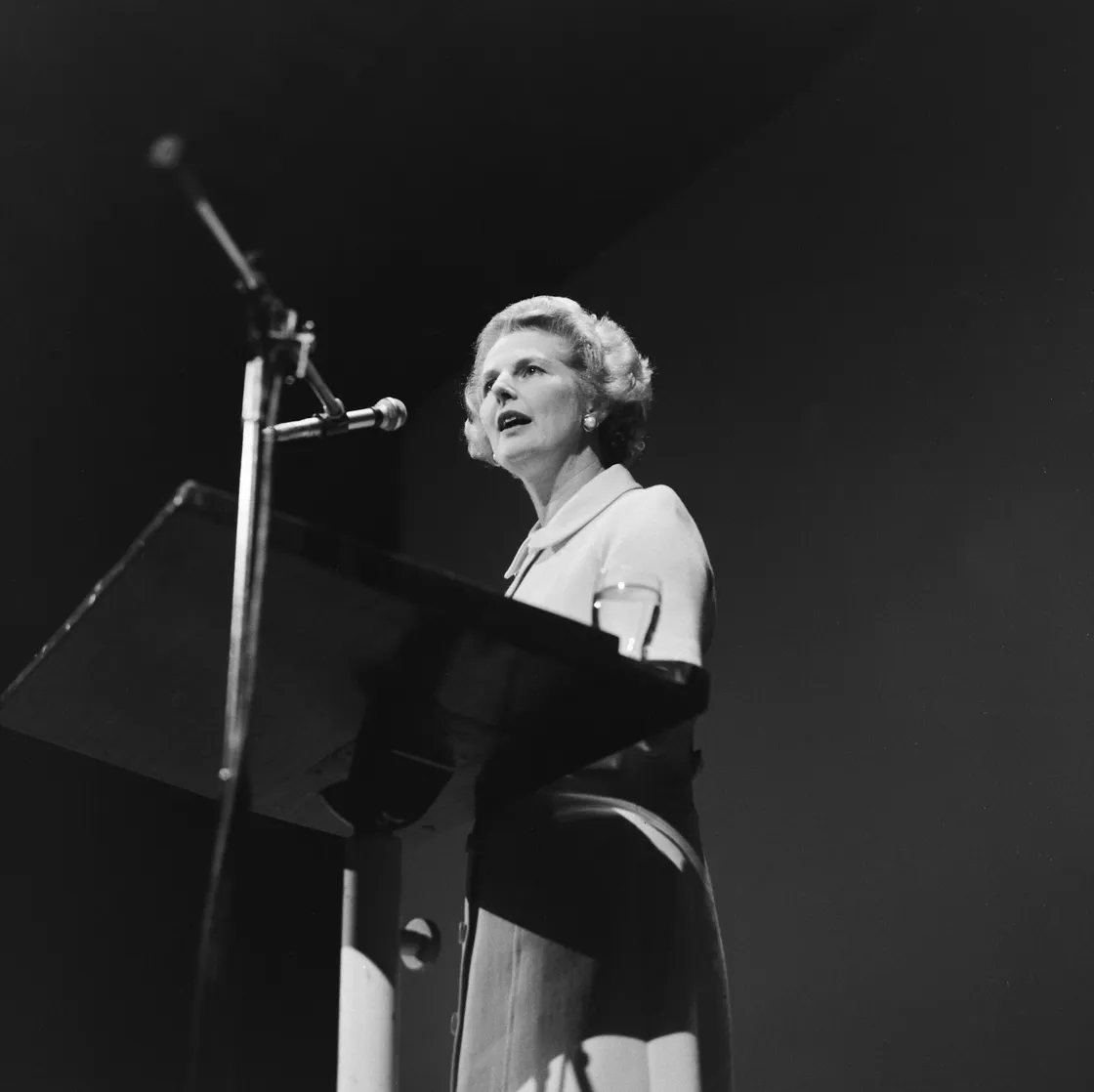 A black-and-white photo of Margaret Thatcher speaking passionately at a podium.