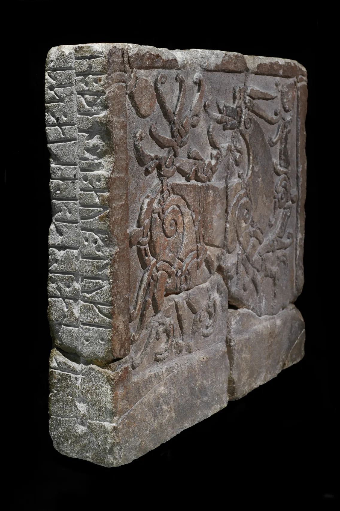 Ancient carved stone relief depicting intricate mythical figures against a black background.