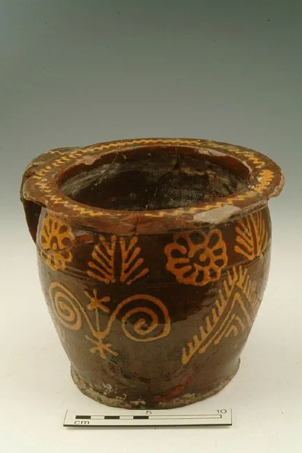 Ancient painted pottery vessel with intricate floral and geometric designs, shown with a scale for size reference.