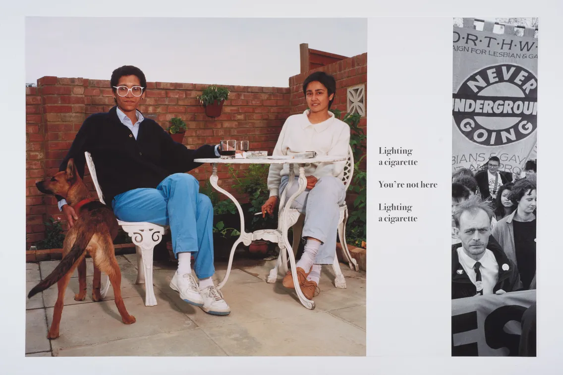 A man and a woman sitting on patio chairs, the man lighting a cigarette, with a dog beside them and a tray with drinks on the table. Background shows various posters with text and images.