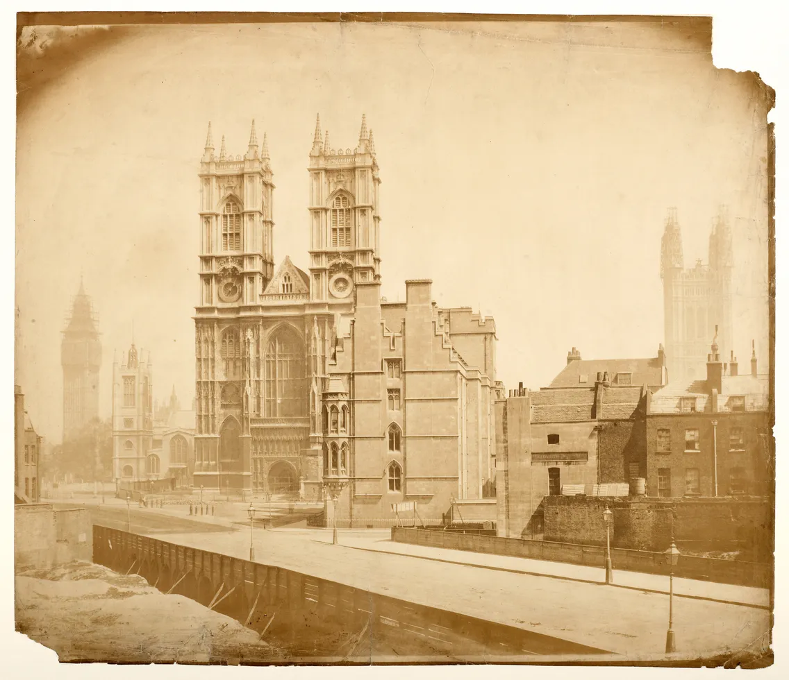 Historic sepia-toned photograph of the westminster abbey facade with surrounding buildings, captured in the early 20th century.